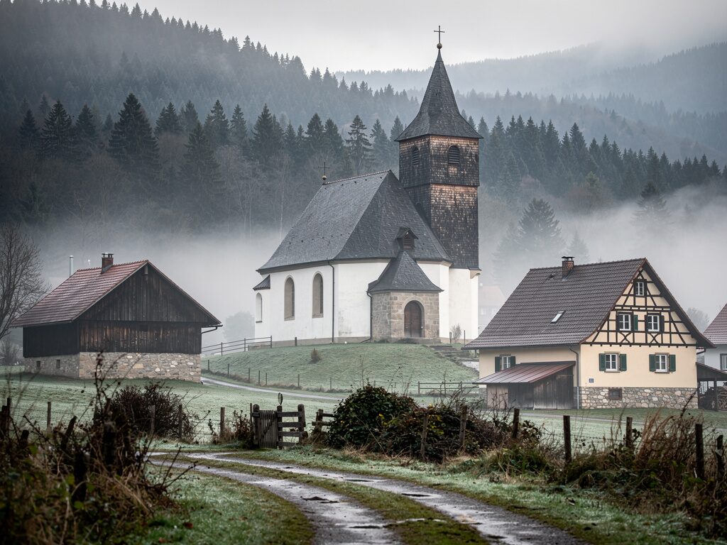 Schwarzwald-Dorfkirche im Morgennebel mit Tannenhängen
