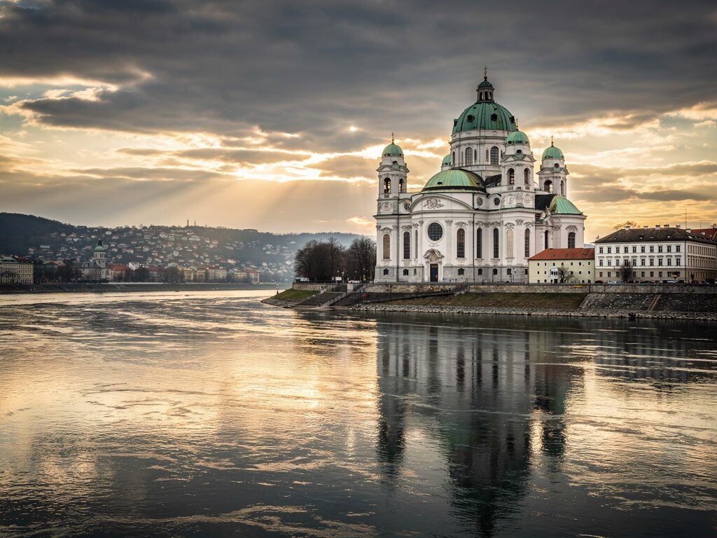 Weiße barocke Domkirche mit grünen Kuppeln über der Donau in Passau