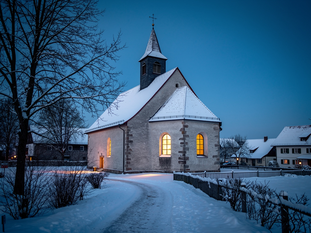 Verschneite Dorfkirche am Adventsabend mit warmem Kerzenlicht in den Fenstern
