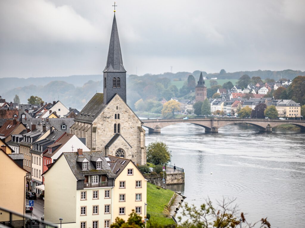 Evangelische Stadtkirche mit Schieferturm in einer Rheinstadt mit Brücken