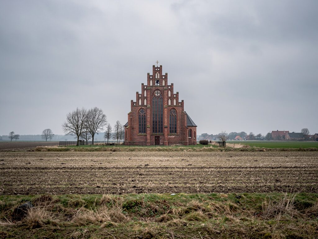 Norddeutsche Backsteingotik-Kirche in flacher Feldlandschaft